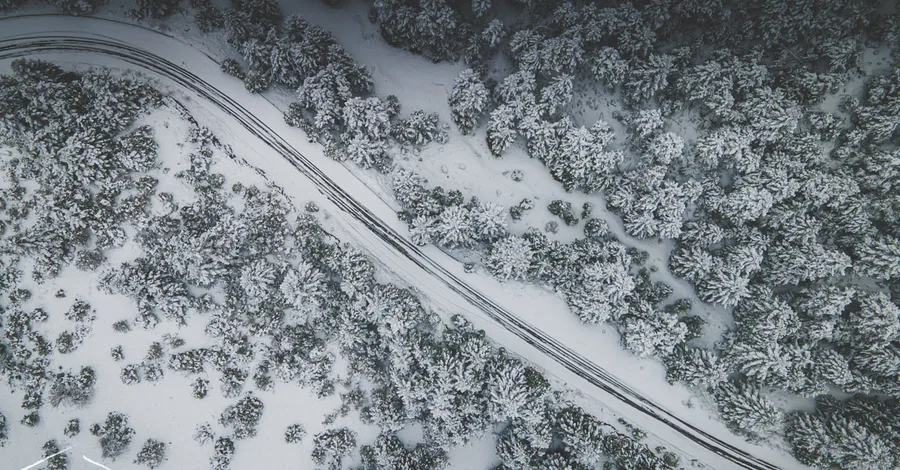 A road cutting through snowy forest, from above