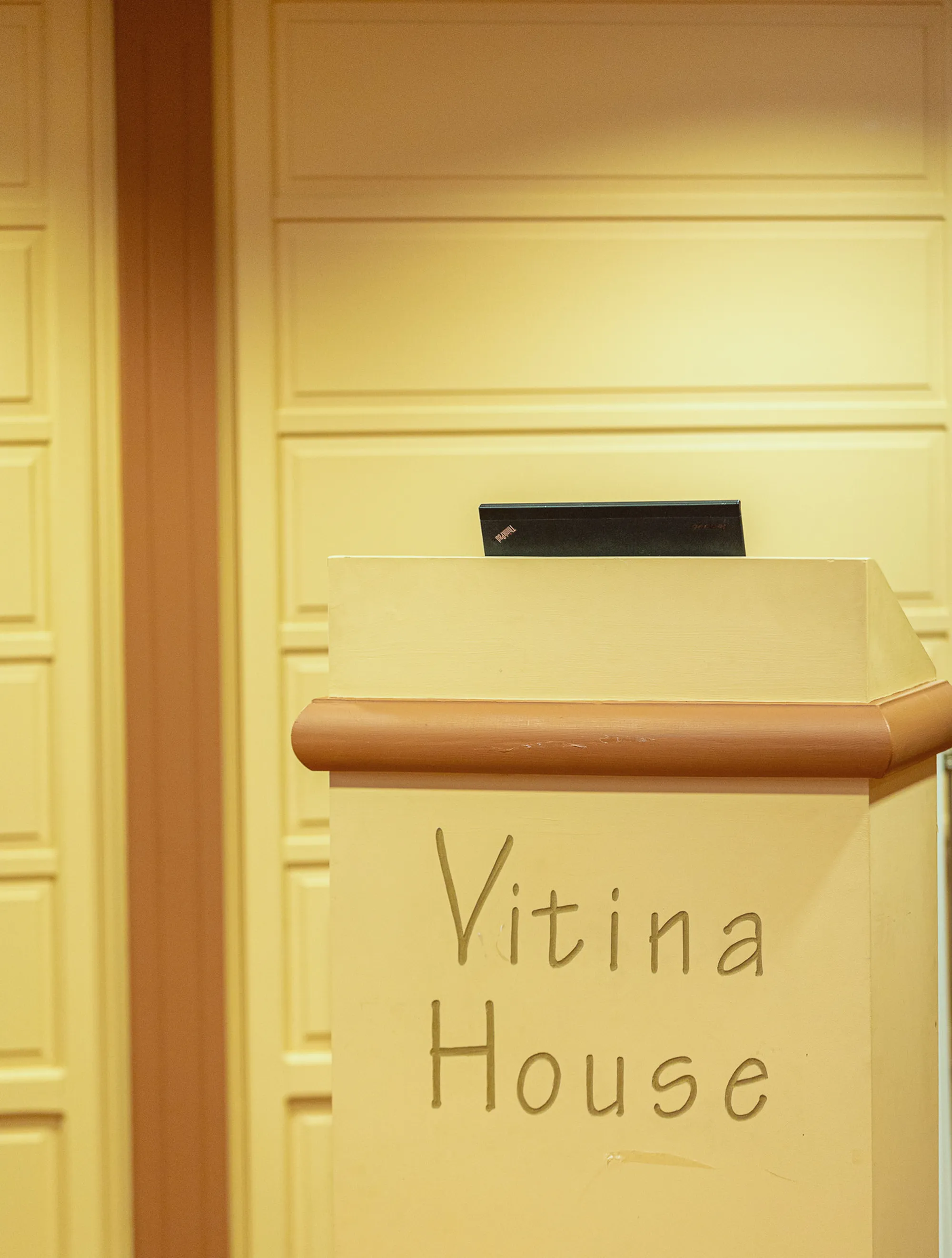 A wooden lectern with the words Vitina House on its front
