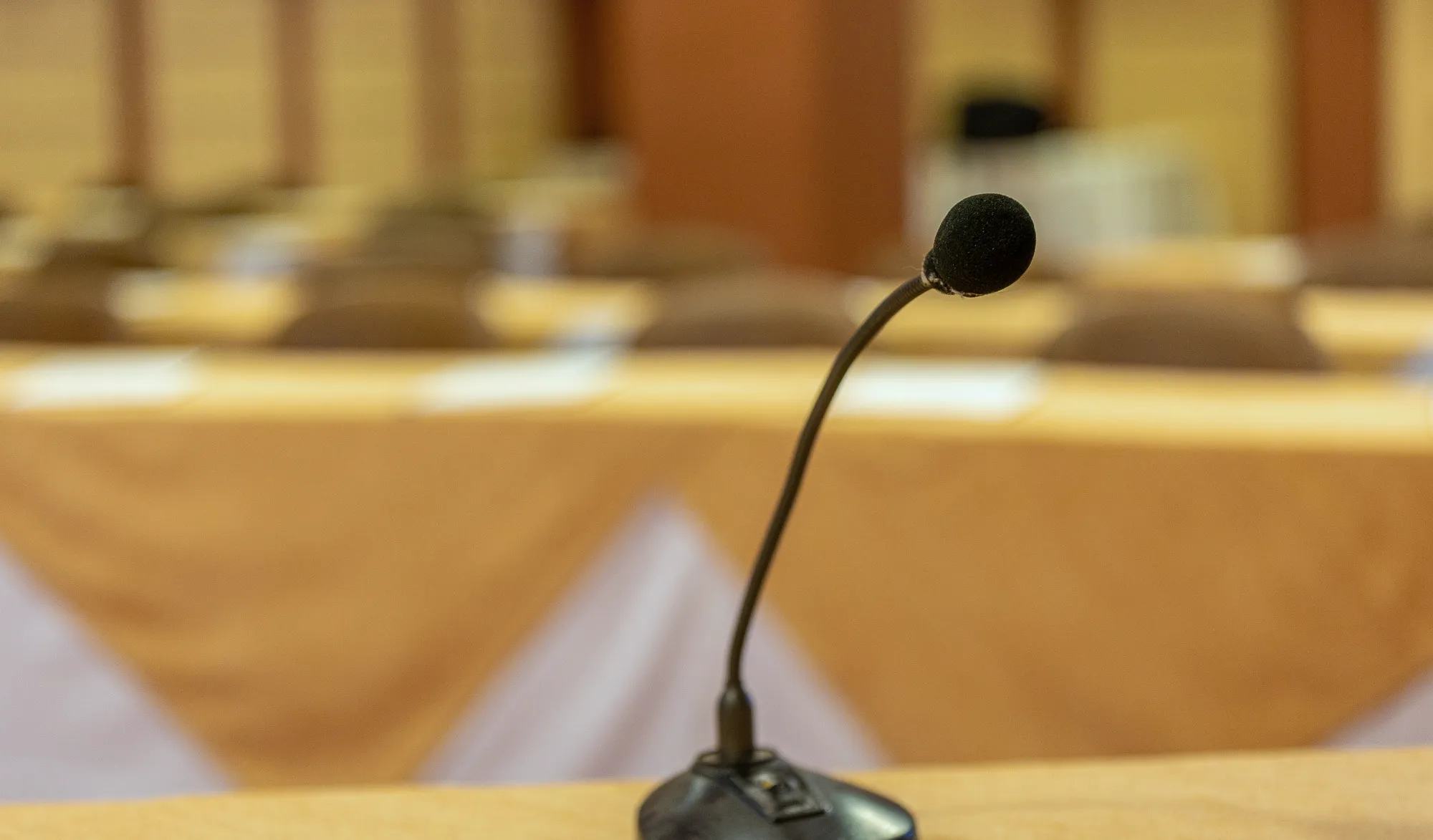 A table microphone on a stand, with rows of tables out of focus behind it