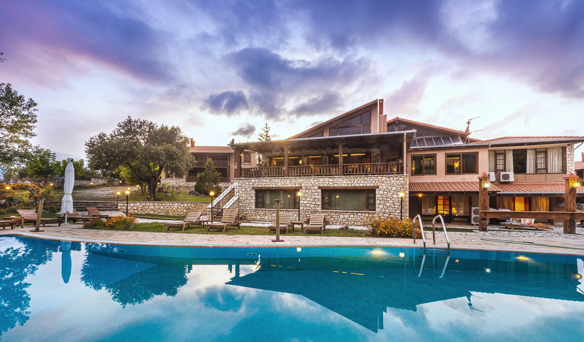 The main building of Vitina House at dusk, reflected in the pool