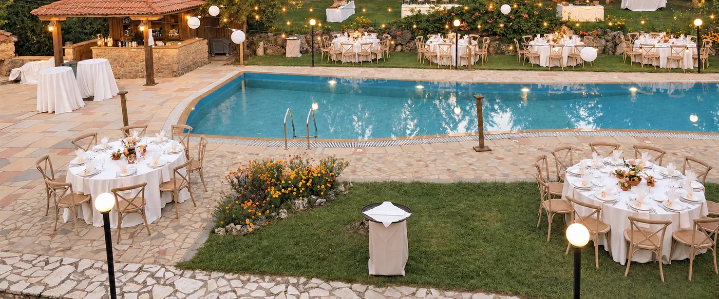 The pool and the tables laid around it as the lights come on at dusk, with the gazebo bar on the left