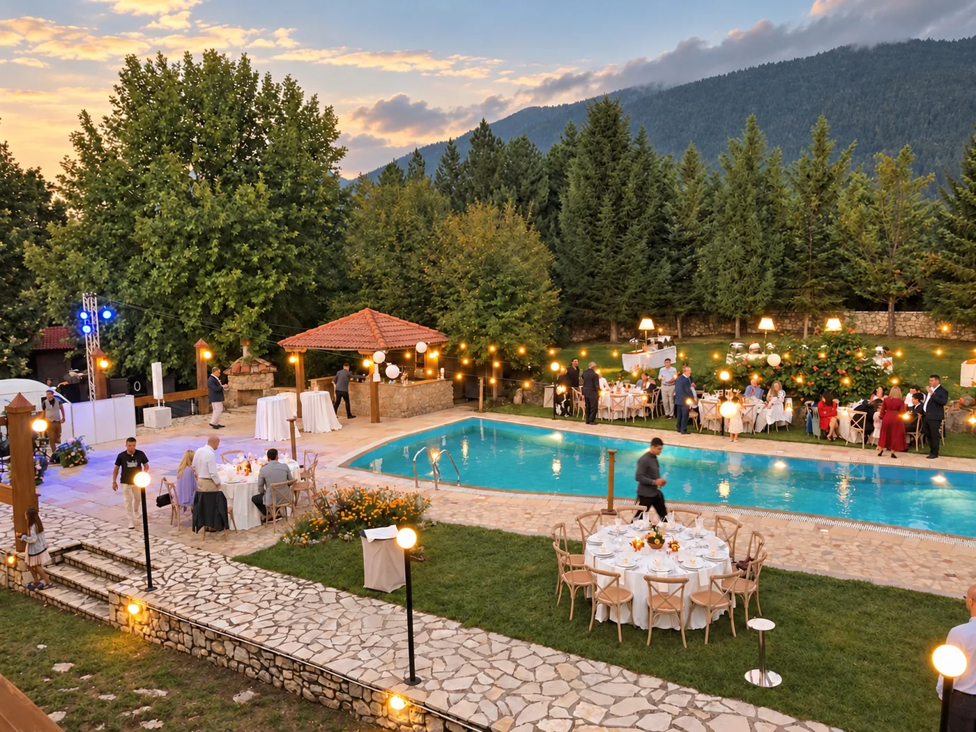 Dusk at the reception, with the pool lit, guests on the terrace and music equipment set up on the left