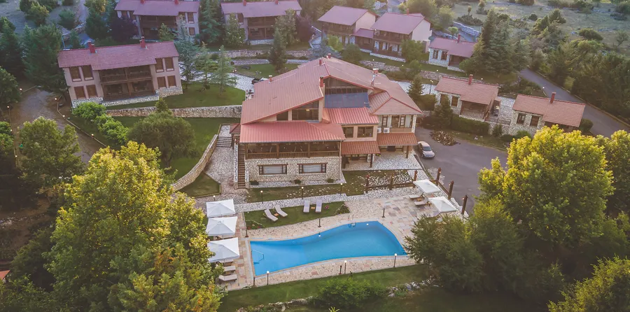 Εναέρια λήψη του ξενοδοχείου: κόκκινες στέγες, η πισίνα και οι κήποι