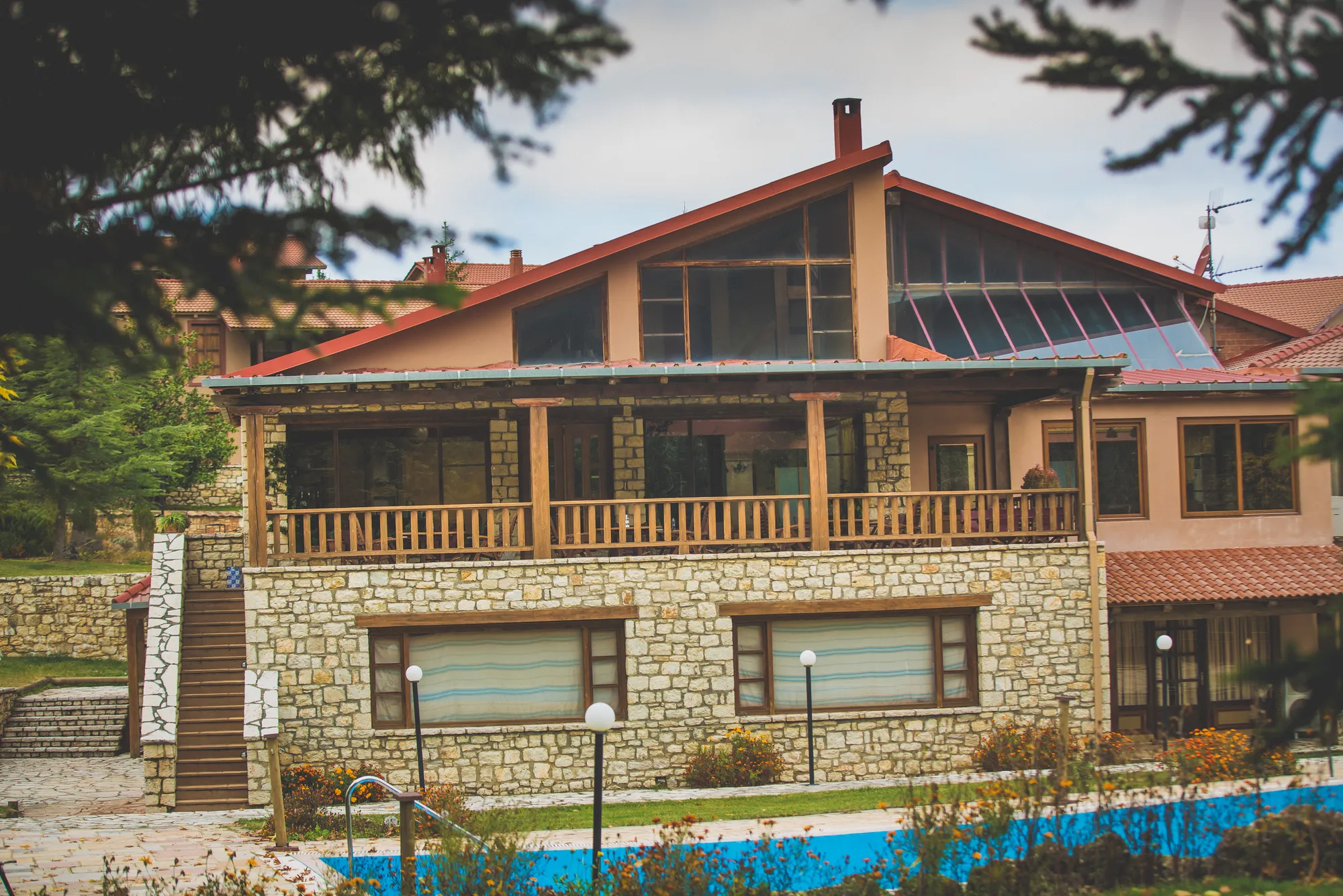 The main building of Vitina House with its timber balcony and the pool in front
