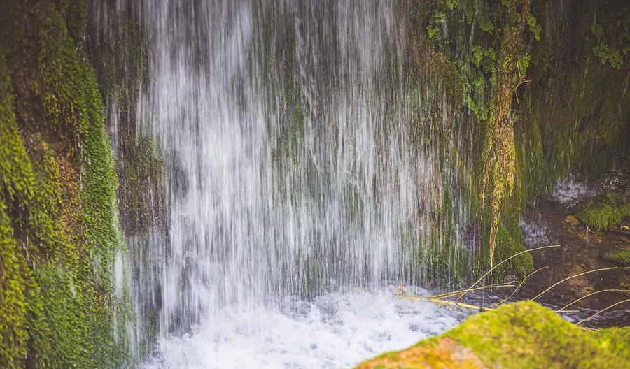 A waterfall falling into a green pool