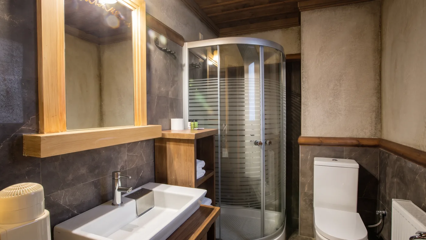 Bathroom with a glass shower enclosure, a white basin and a wide wooden-framed mirror