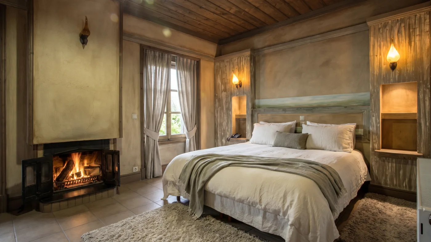 Premium room with a lit fireplace beside the double bed and curtained windows