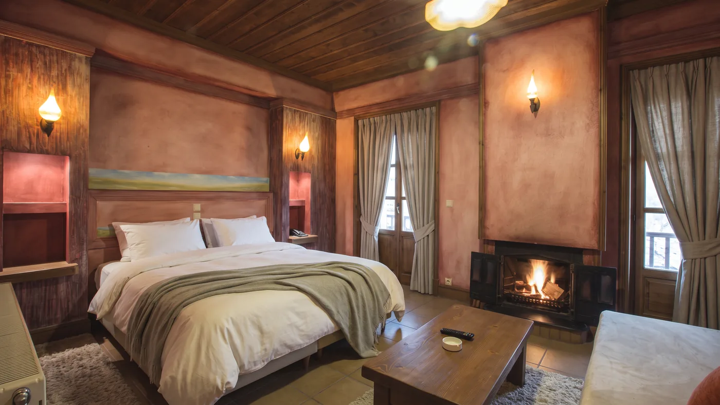 Premium room with painted walls, a fireplace glowing next to the bed and a ceiling lamp above