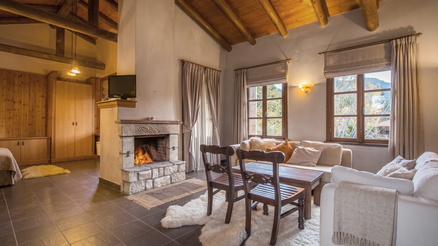 Villa living area with a stone fireplace, log beams and sofas by the windows