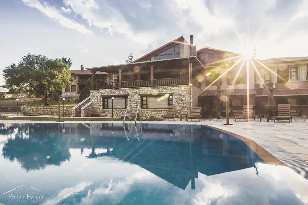 Η πισίνα και το κεντρικό κτίριο του Vitina House στο χρυσό φως