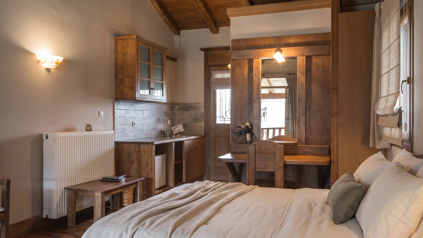The Standard room kitchenette with wooden cabinets, a sink and a mini fridge beside the bed