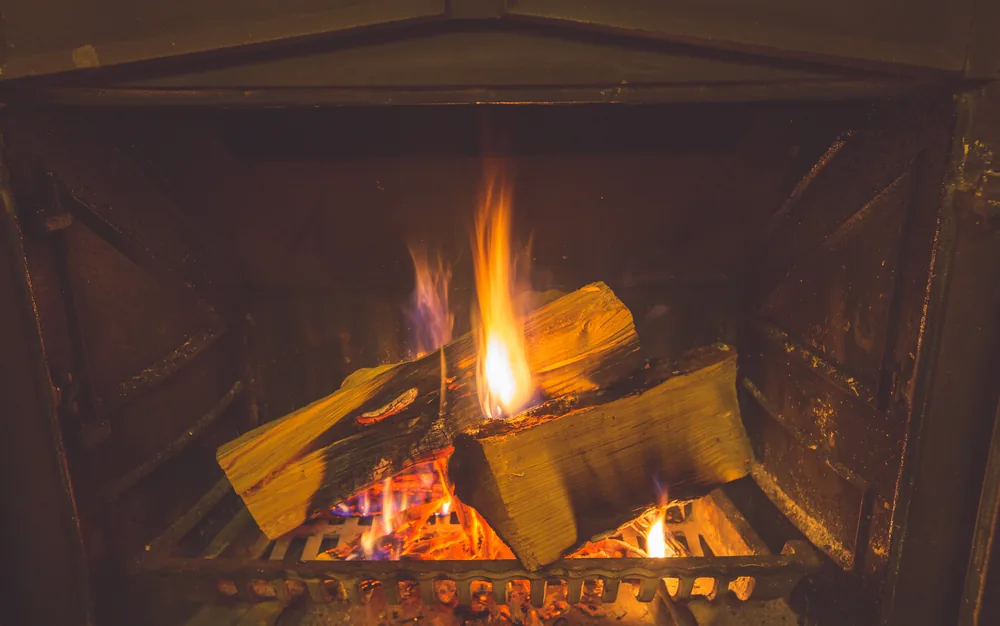 Logs burning on an iron grate in a fireplace