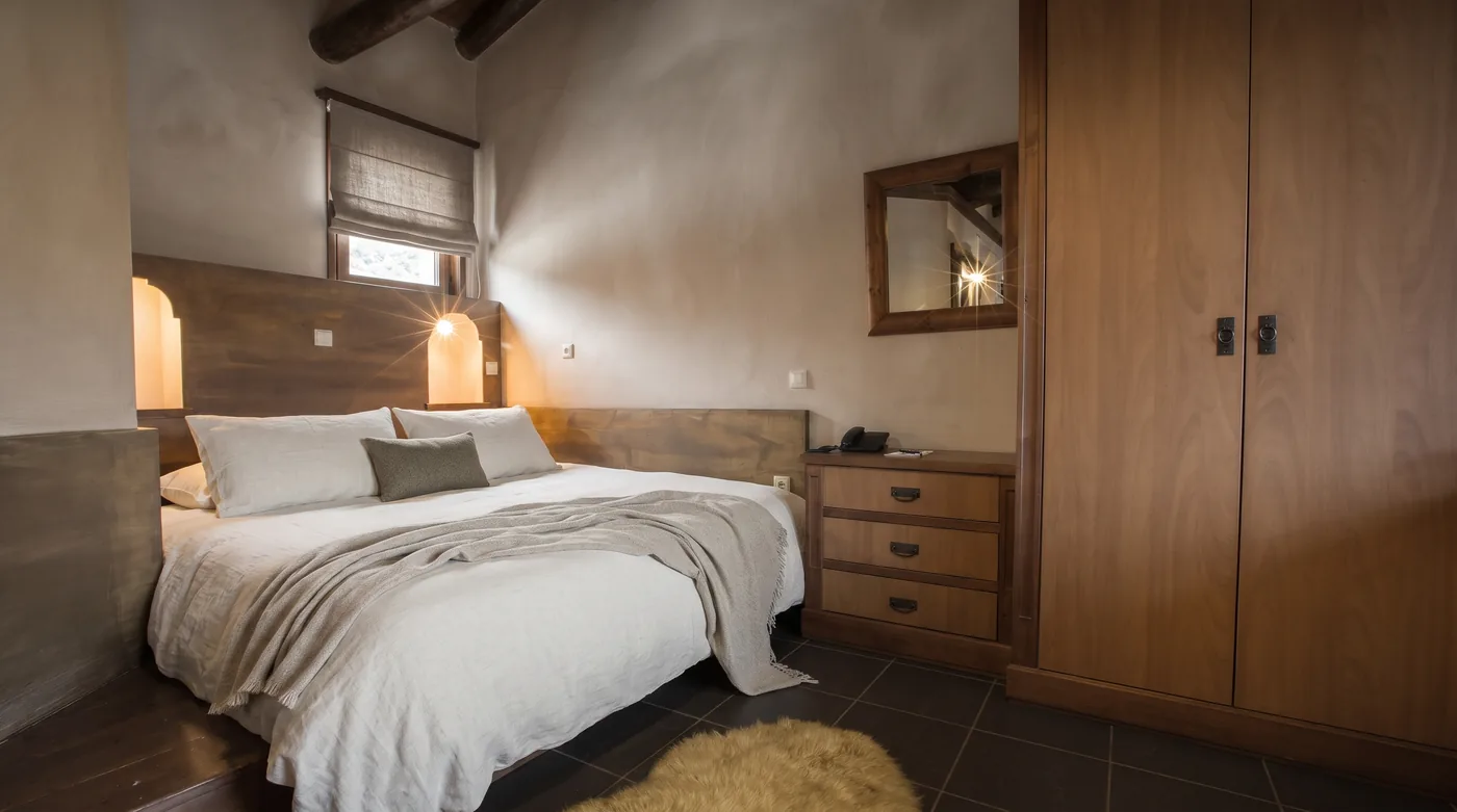 Villa bedroom with a wide bed, a carved wooden headboard, a chest of drawers and a tall wardrobe